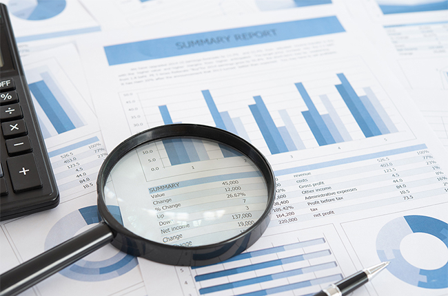 Magnifying glass sits on print outs of data analysis tables