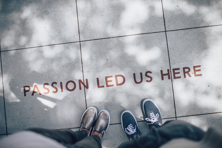 Two people stand and look down at the sidewalk, which has the message